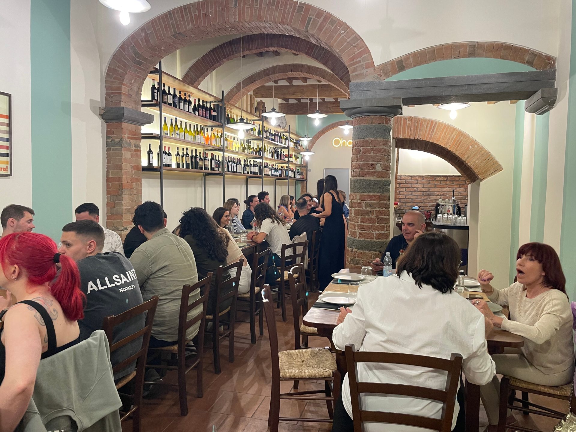 La sala dell'osteria Ohana a Empoli: volte in mattoni, cantina a vista e tavoli apparecchiati